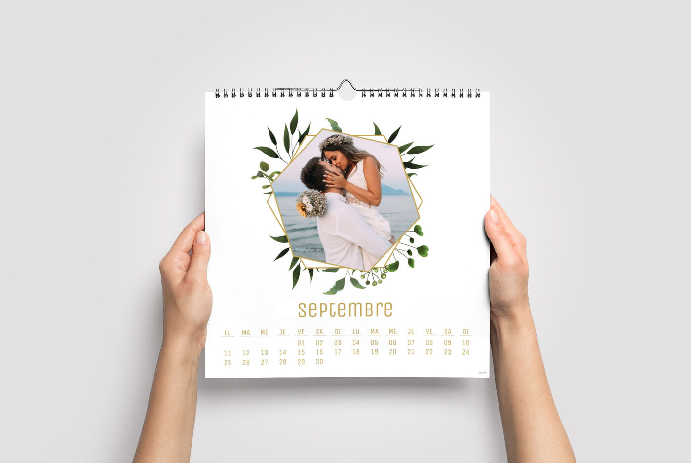 Une personne tient un calendrier photo CEWE d'un couple dans une tendre étreinte, mois de septembre.
