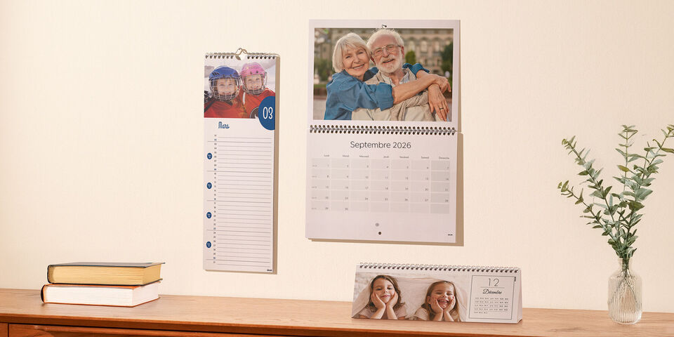 Deux calendriers CEWE accrochés au mur et un calendrier ABM sur une table