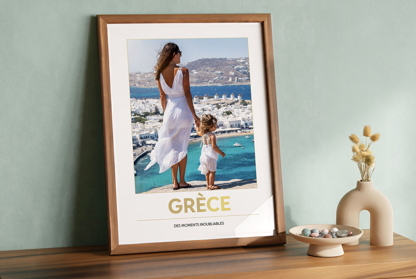 Un enfant et une femme en robe blanche se tiennent au bord d'une falaise avec vue sur la mer en Grèce.