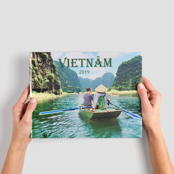 Une personne montre fièrement un album photo sur le Vietnam, entourée de verdure.