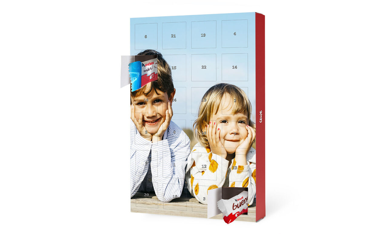 Deux personnes souriant derrière un calendrier de l'Avent, illuminé par le soleil