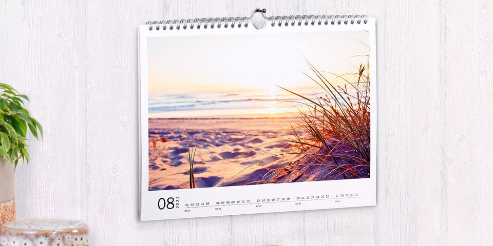 Un calendrier photo CEWE montre une belle plage au lever du soleil, des vagues douces touchent le sable.
