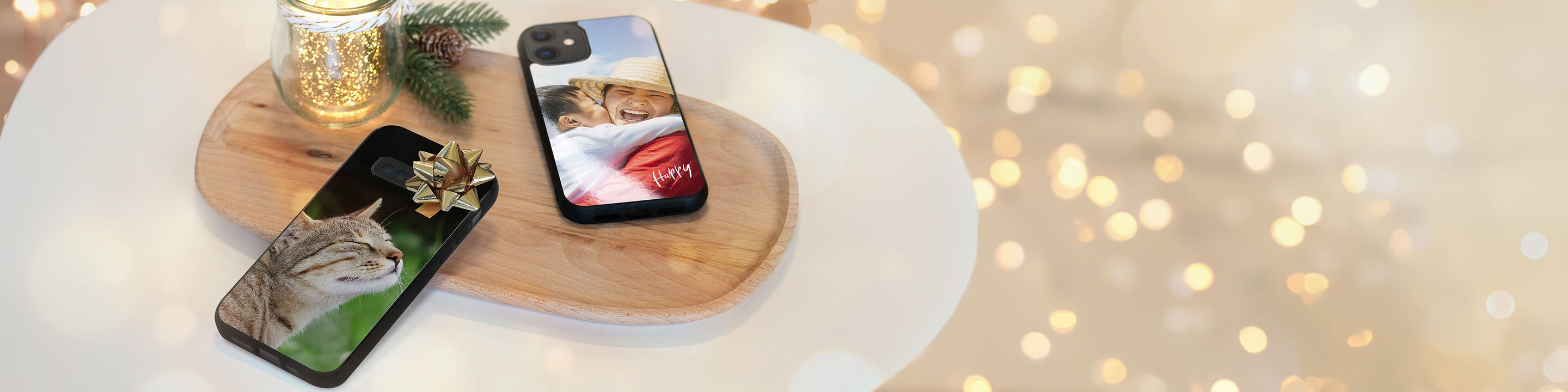 Deux smartphones au design unique sur un plateau en bois, décorés pour Noël avec des lumières douces.