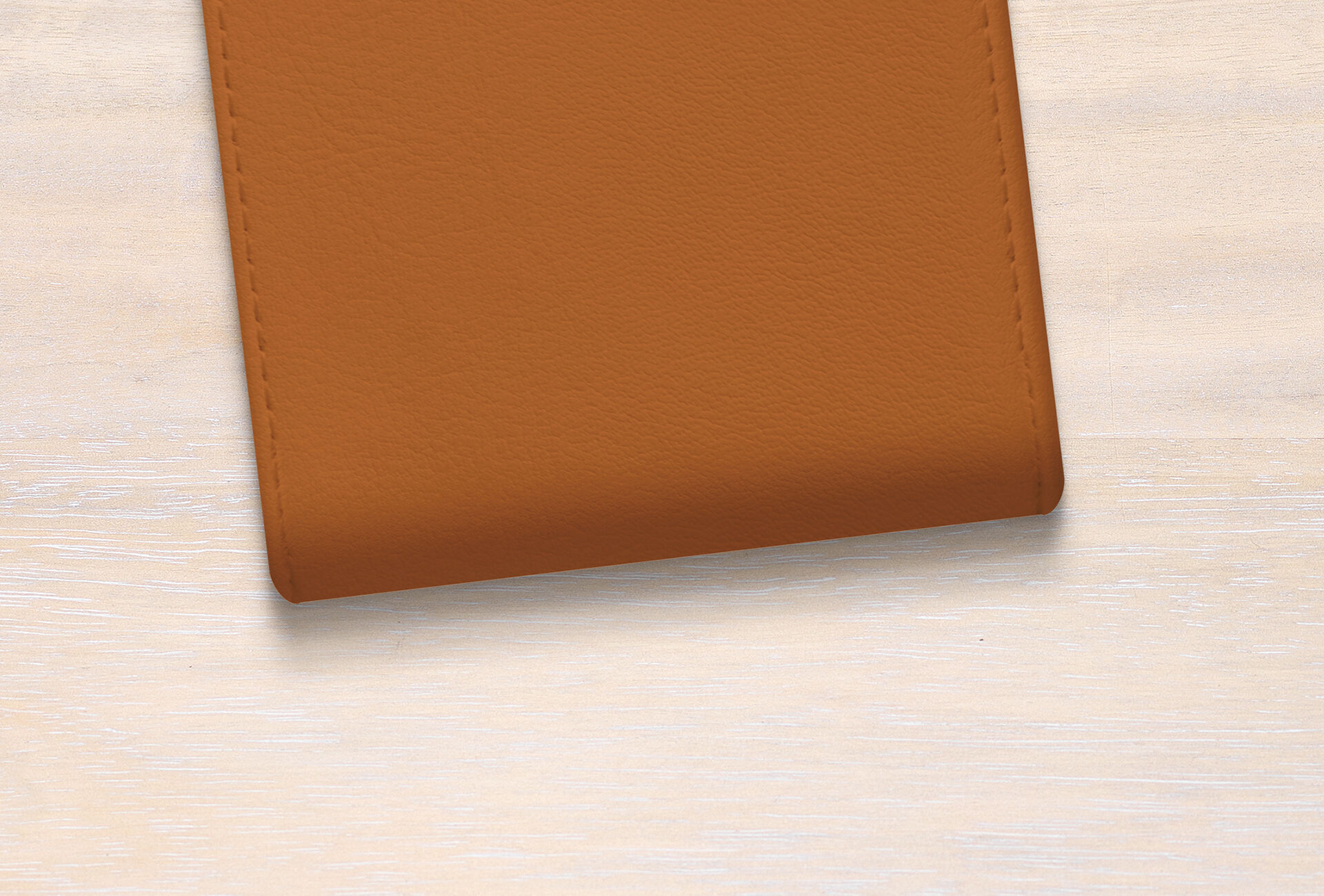 Housse en cuir brun sur une table en bois clair.