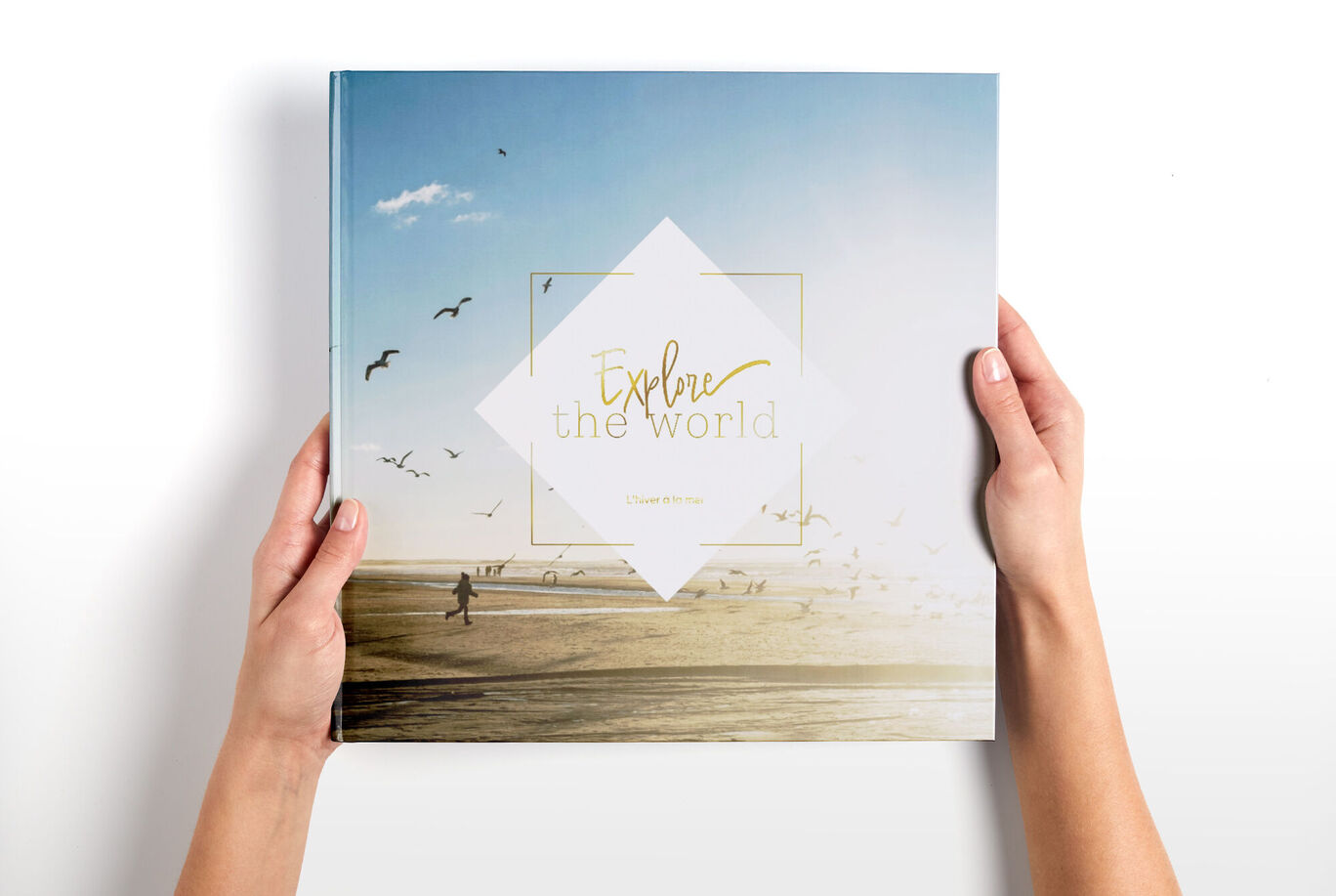 Une personne tient un album photo CEWE intitulé "Explorer le Monde".