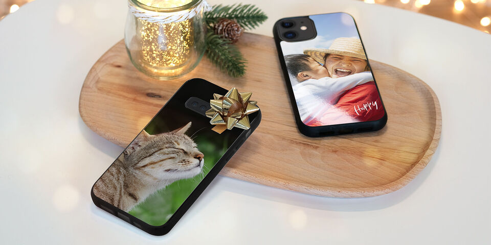 Un élégant plateau montre deux téléphones avec des motifs personnels. L'un montre un chat, l'autre un message de Noël.