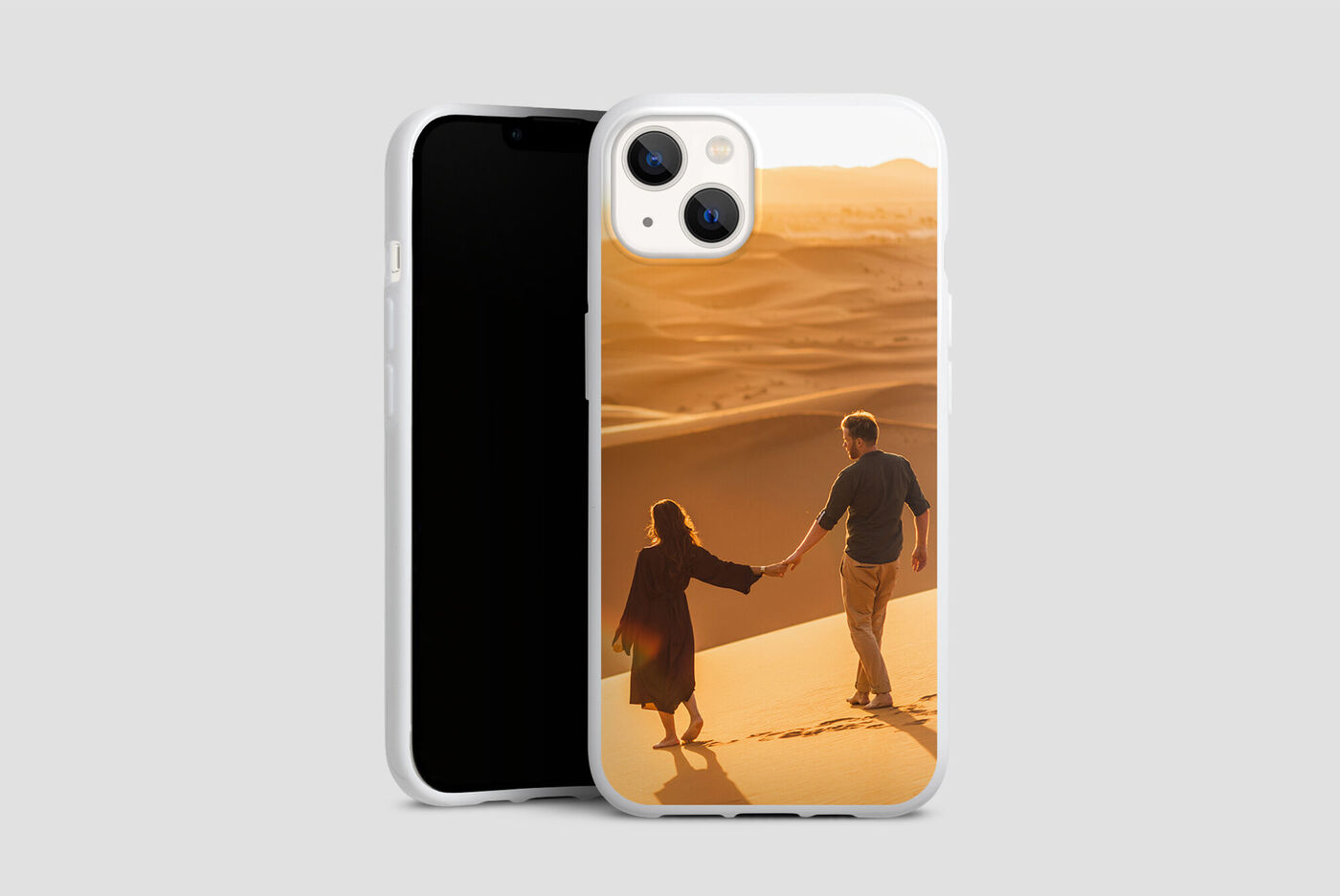 Un couple se tient par la main et marche à travers des dunes de sable au coucher du soleil