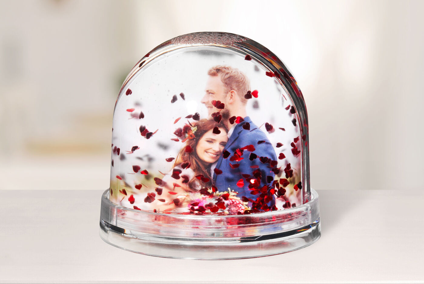 Un globe en verre rempli de confettis en cœur montrant une scène romantique.