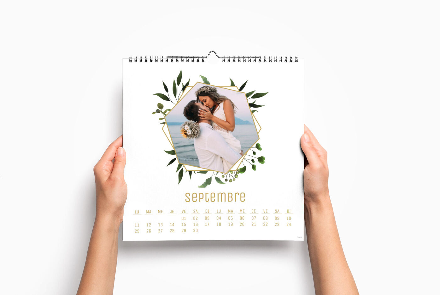 Une personne tient un calendrier photo avec une image romantique d'un couple à la plage.