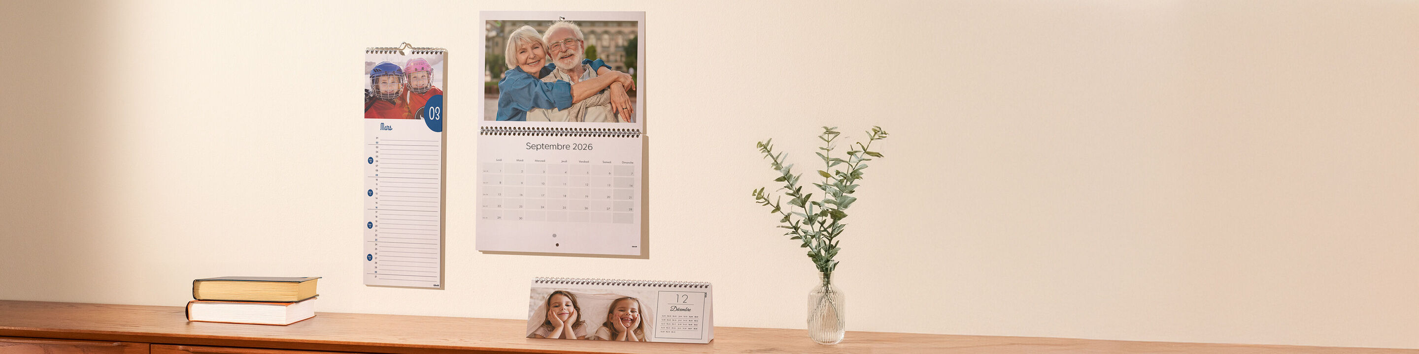 Un beau calendrier mural est accroché au mur, avec des photos d'une famille souriante et un petit bouquet à côté.