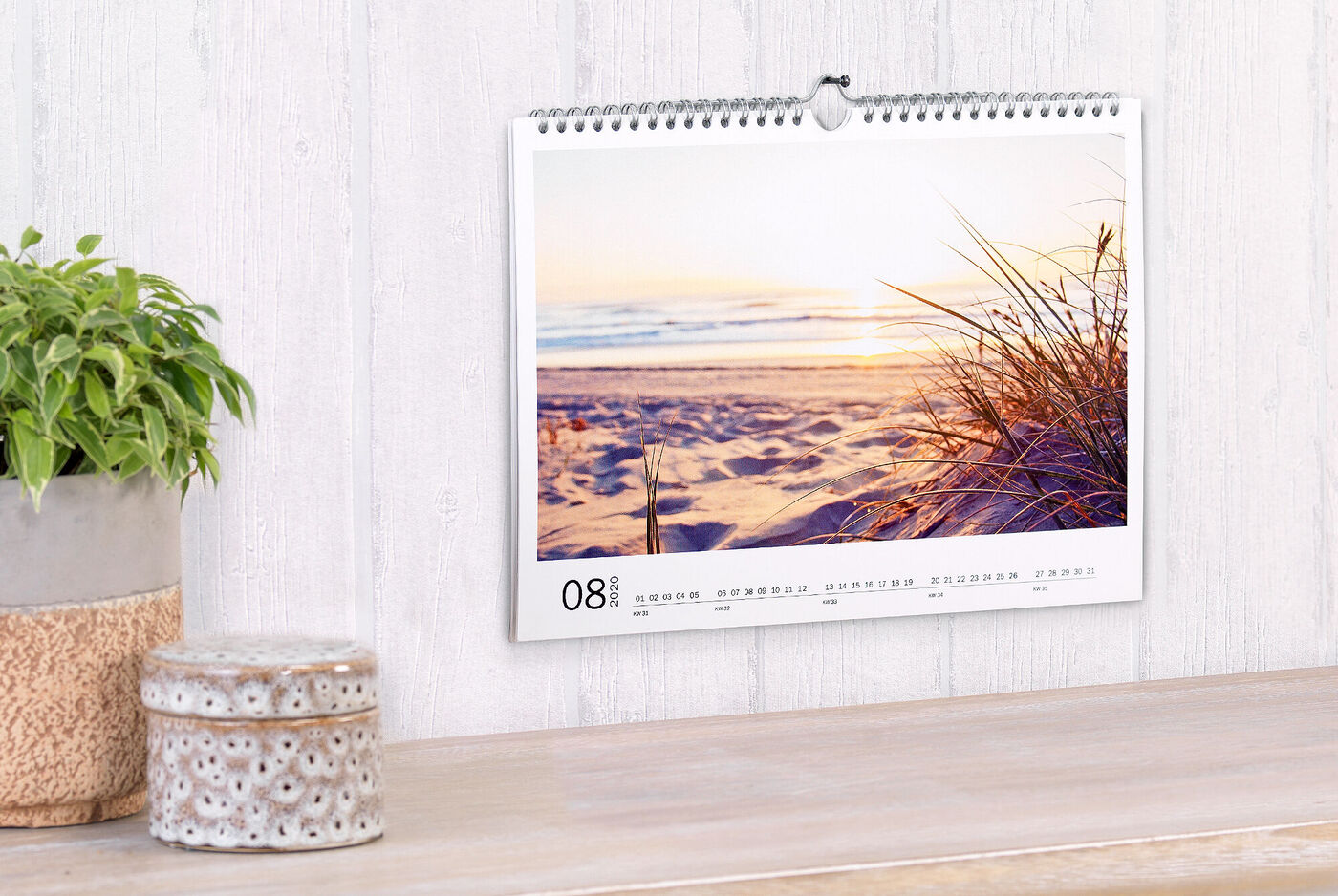 Un beau calendrier avec un coucher de soleil sur la plage et des herbes douces au premier plan.