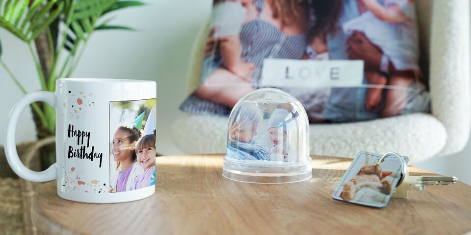 Une tasse avec une photo et un message d'anniversaire, une petite cloche et porte-clé avec photos.