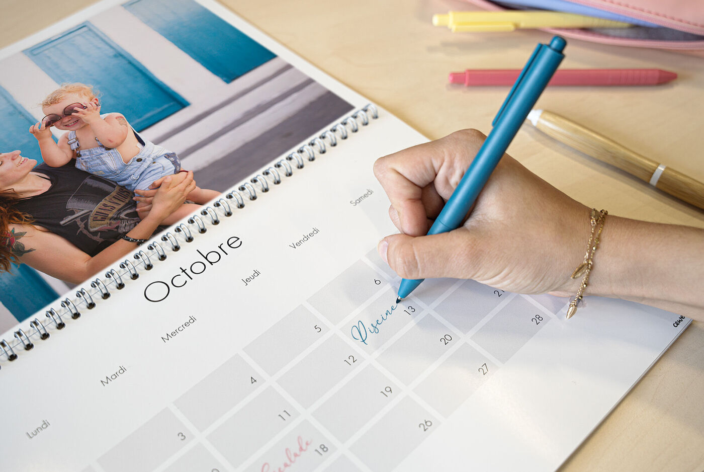Main écrivant dans un calendrier, avec une photo d'un enfant sur une page supplémentaire