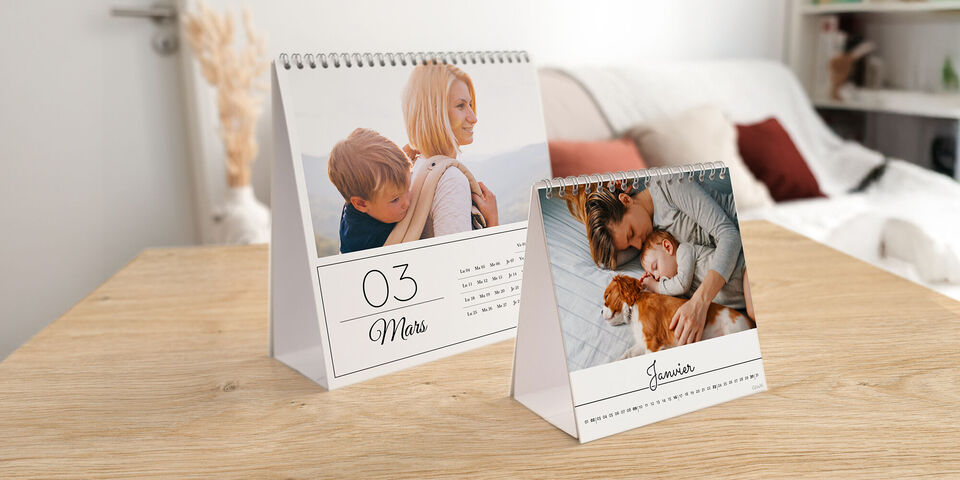 Des calendriers photo créatifs sur une table, l'un avec un garçon et une femme, l'autre avec un homme et un chien. Les deux montrent des moments personnels.