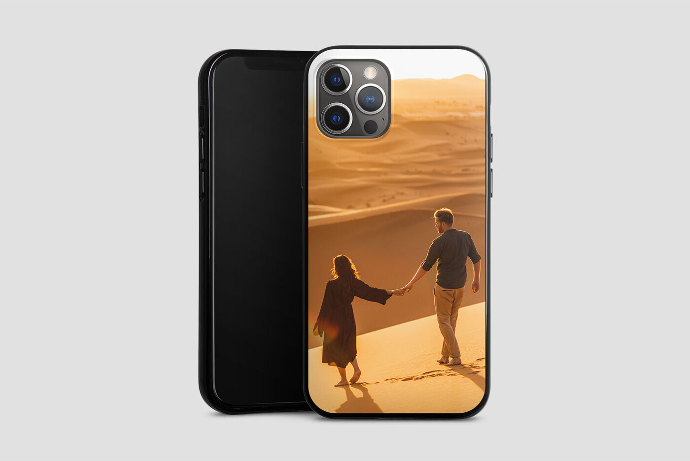 Un couple se tient la main sur une dune de sable au coucher du soleil