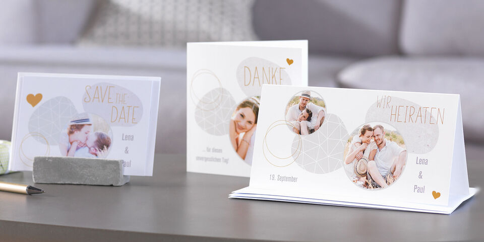 Trois cartes festives sur une table : invitation de mariage, remerciements et carte à enregistrer.