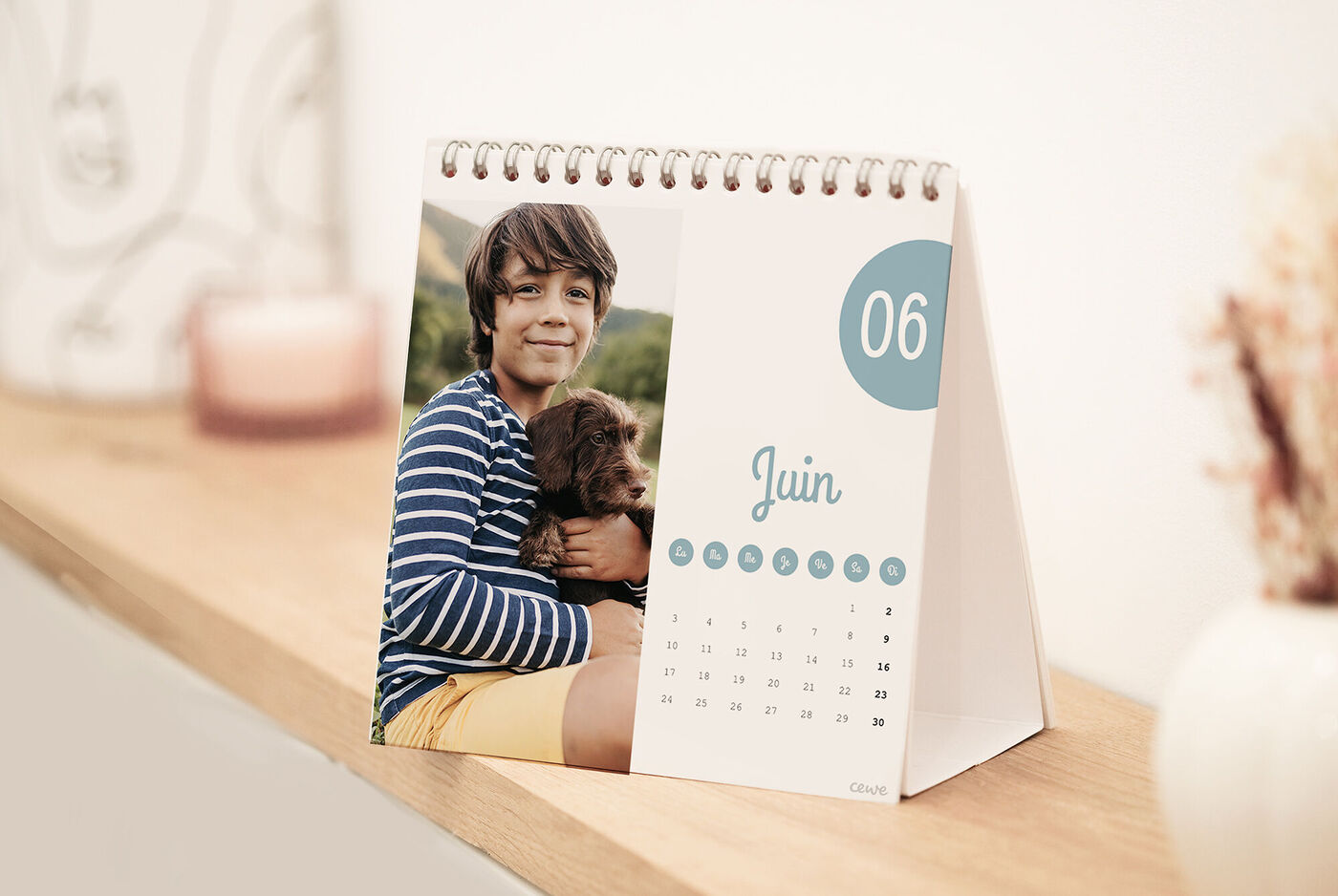 Un calendrier photo CEWE montrant un garçon avec un chien sur une étagère en bois clair.