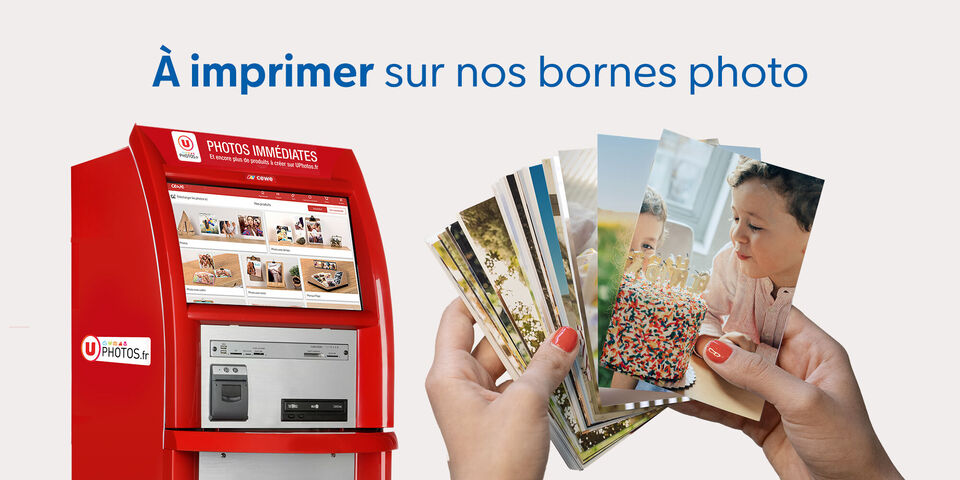 Mains tenant plusieurs tirages photos, à côté d'une borne d'impression photo rouge U Photos