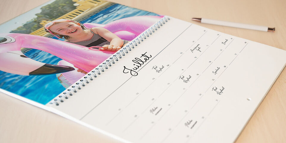 Un enfant joyeux sourit sur un flamant rose dans la piscine, calendrier photo CEWE.