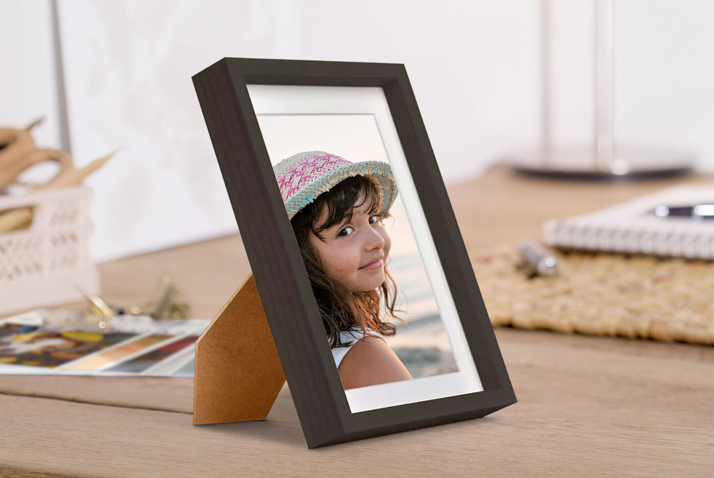 Un beau cadre montre le portrait d'une personne avec un chapeau. Le cadre est sur une table.