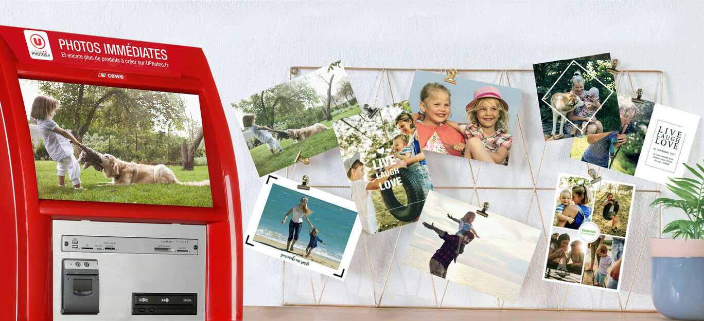 Une borne d'impression photo rouge avec des images de moments heureux à côté, joliment accroché à un support métalique